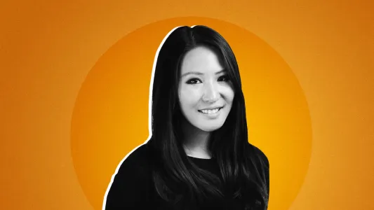 Portrait of a smiling woman with long black hair against an orange background.
