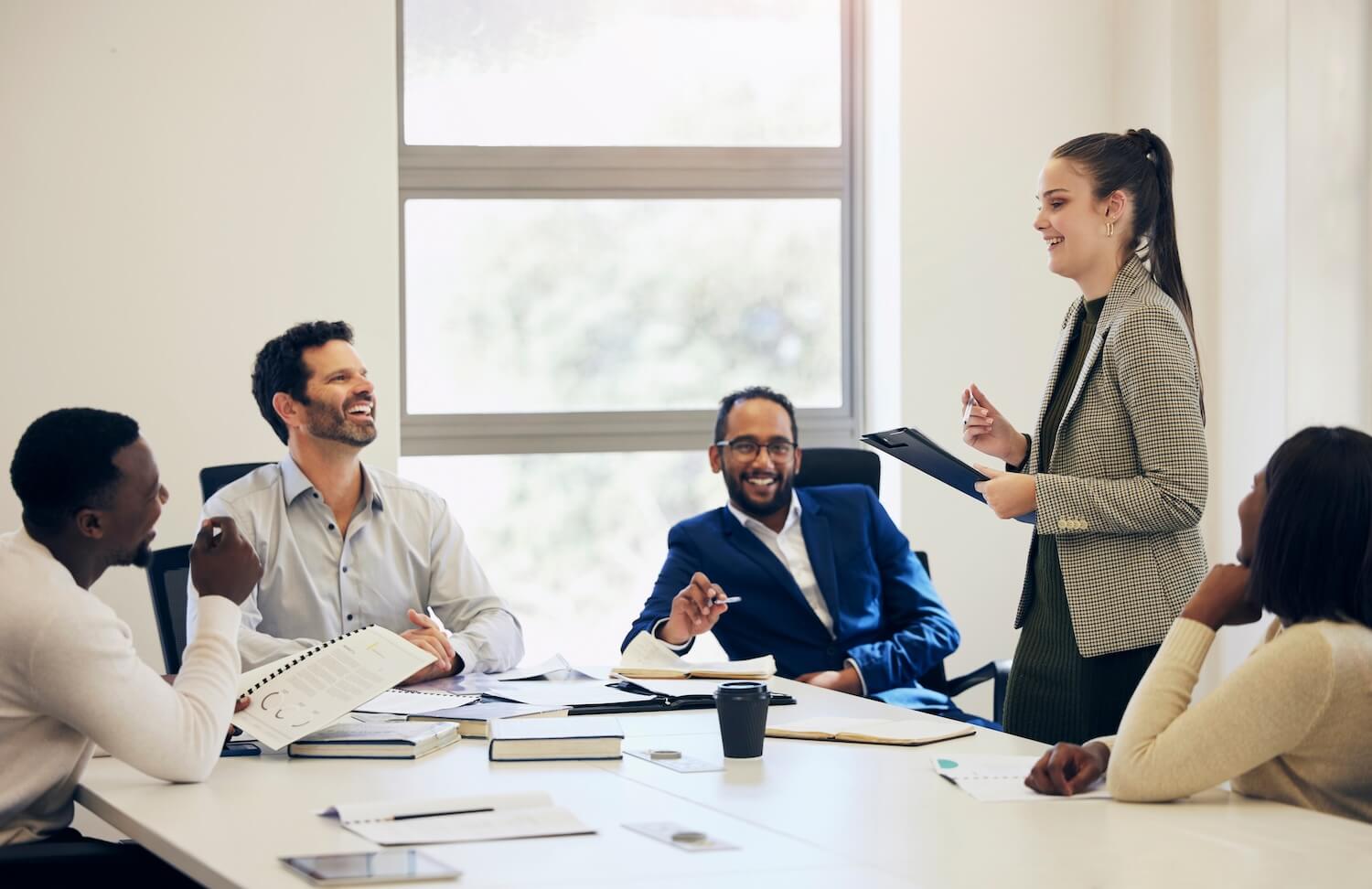 Diverse business team laughing during a meeting, illustrating collaboration and communication as key employee retention measures.