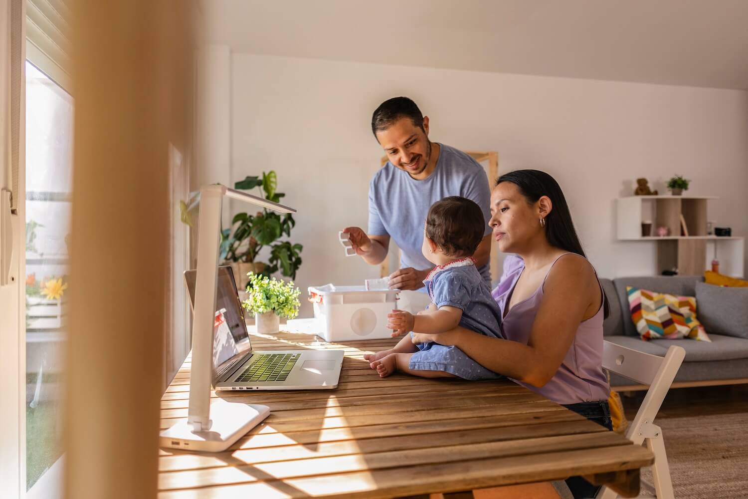 Young family working together from home with a laptop on the table, symbolizing remote work and family-friendly employee retention measures.