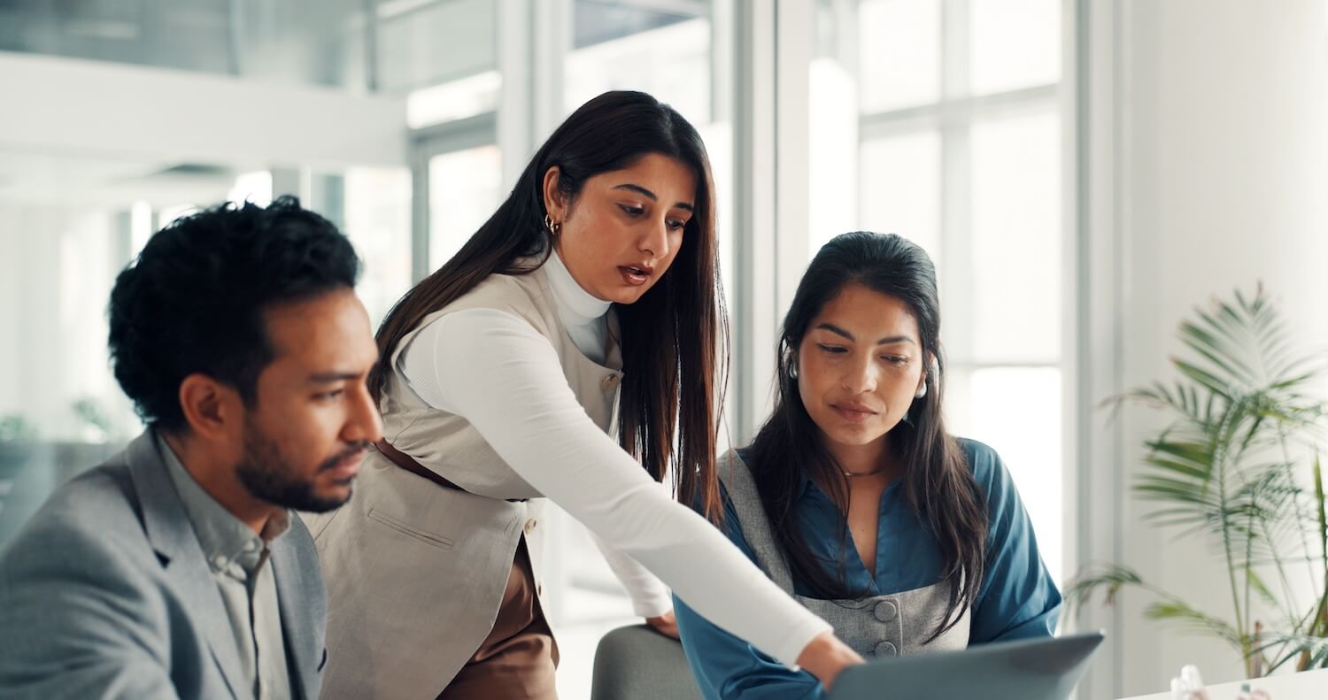 Business professionals analyzing coaching data on a laptop during a meeting, illustrating measuring B2B coaching success in a corporate environment.