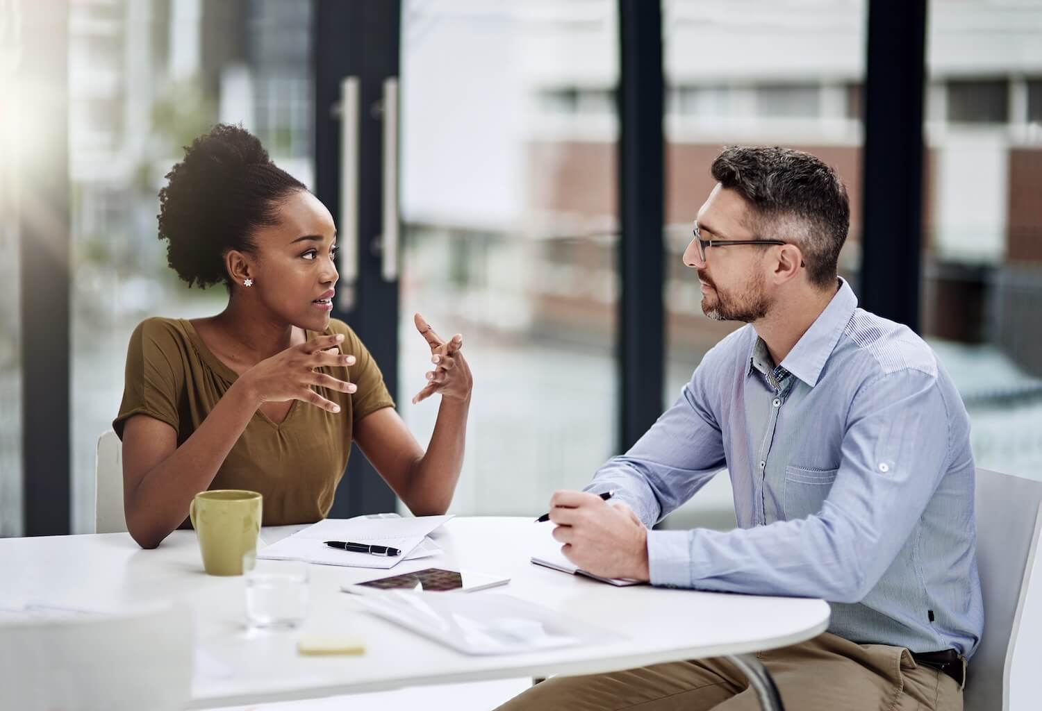 Ein Mitarbeiter gibt konstruktives Feedback in einem Gespräch mit Kollegen in einer modernen Büroumgebung.