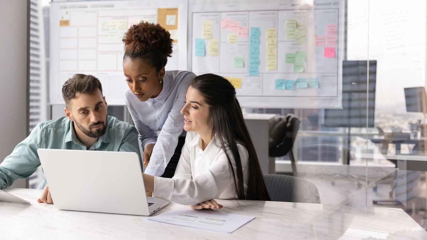 Workshop zu Change-Management-Modellen: Team arbeitet gemeinsam an einem Laptop, im Hintergrund sind eine Planungstafel und Haftnotizen zu sehen.