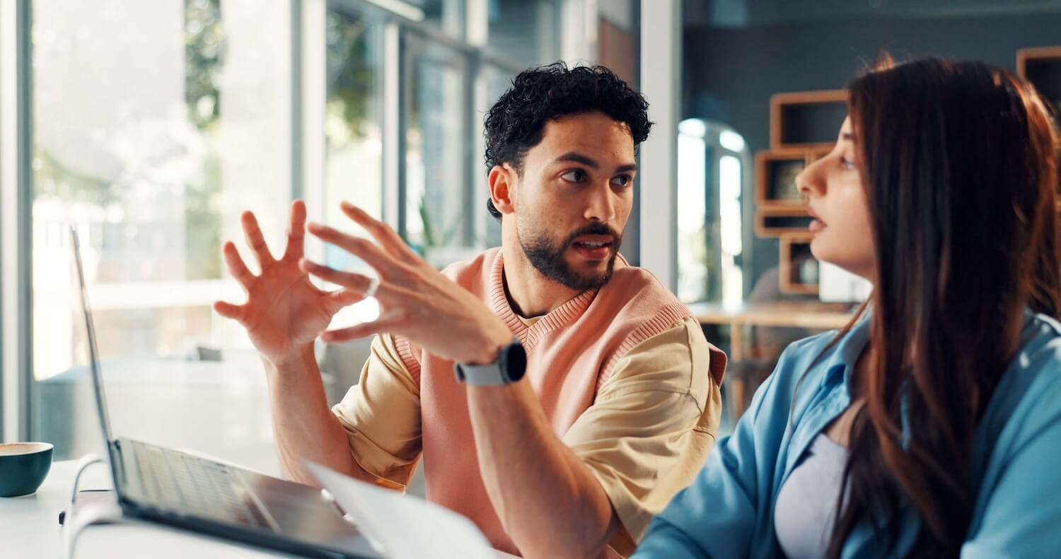 Meeting zu Change-Management-Modellen: Zwei Kollegen besprechen die Umsetzungsschritte neben einem geöffneten Laptop in einem hellen Büro.