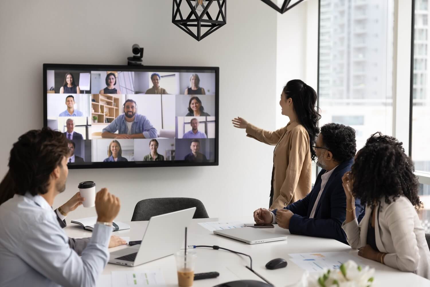 Team participating in a video conference on a large screen, demonstrating Remote Leadership and virtual team collaboration.