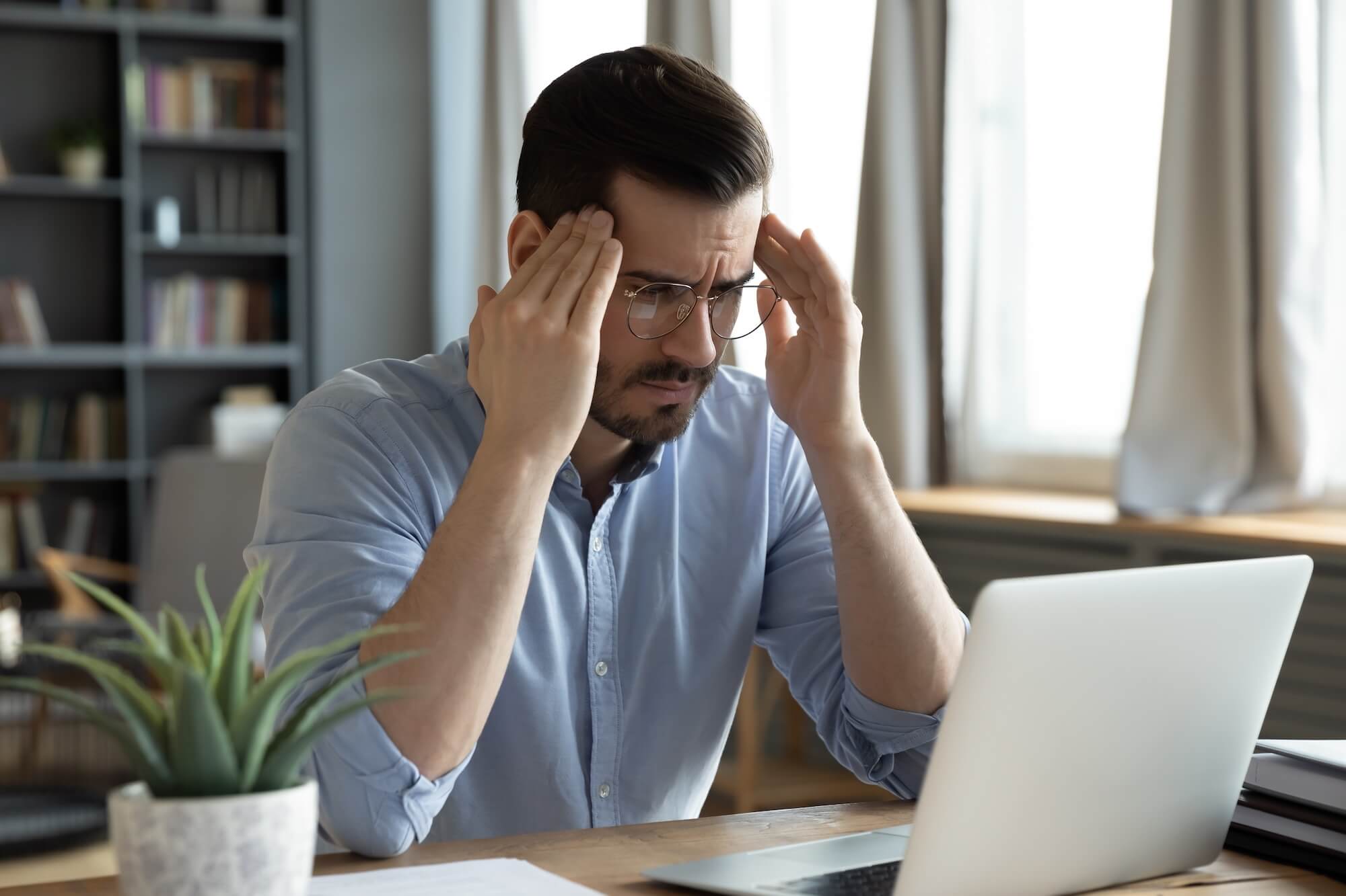 HR is administratively overloaded: A man sits exhausted at his laptop and feels overwhelmed.