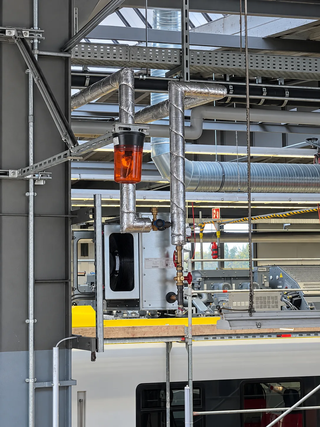 Lüftungstechnik in einer Werkhalle über einem Schienenfahrzeug