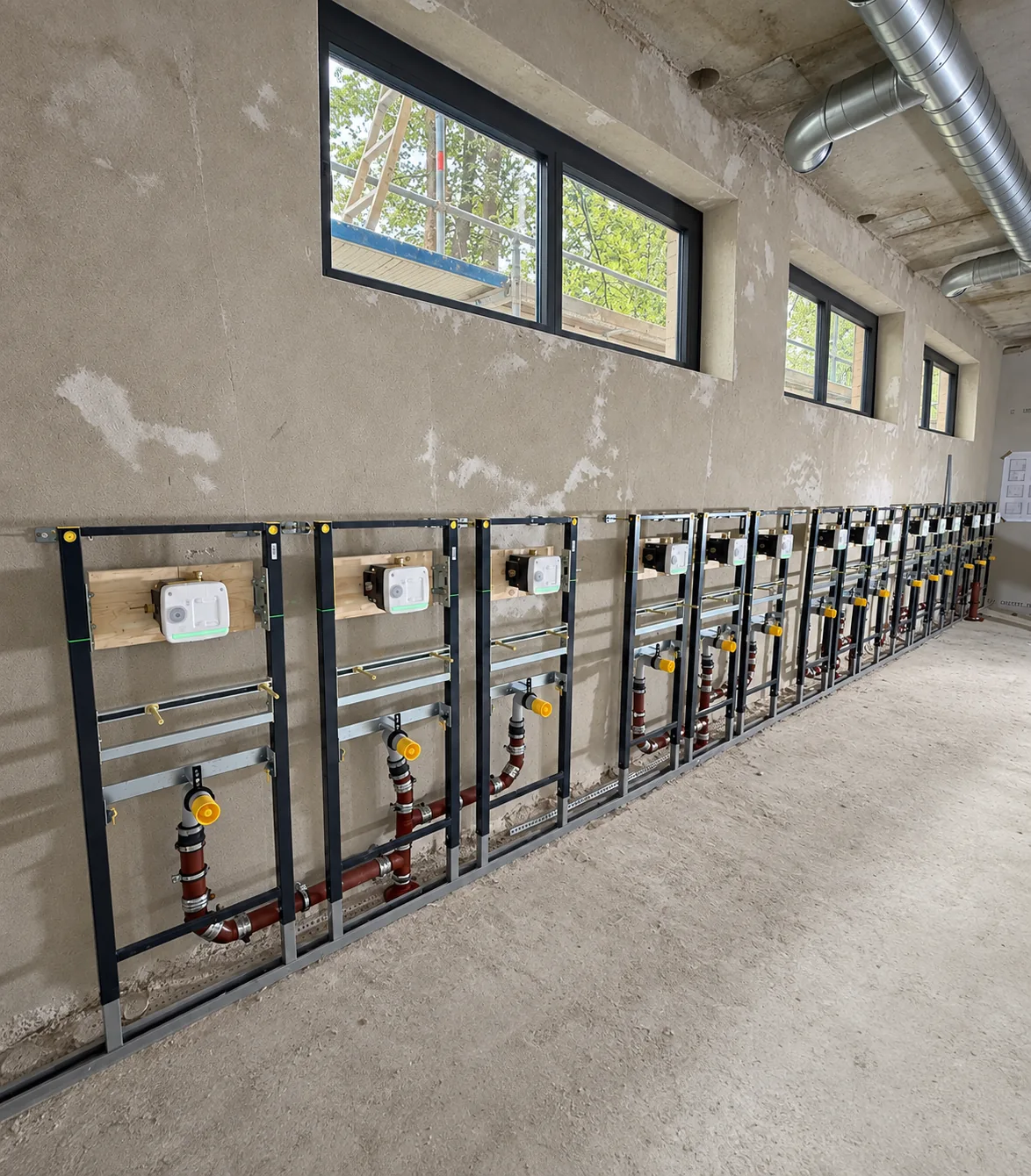 Lange Reihe von WC-Vorwandelementen im Rohbau eines öffentlichen Gebäudes