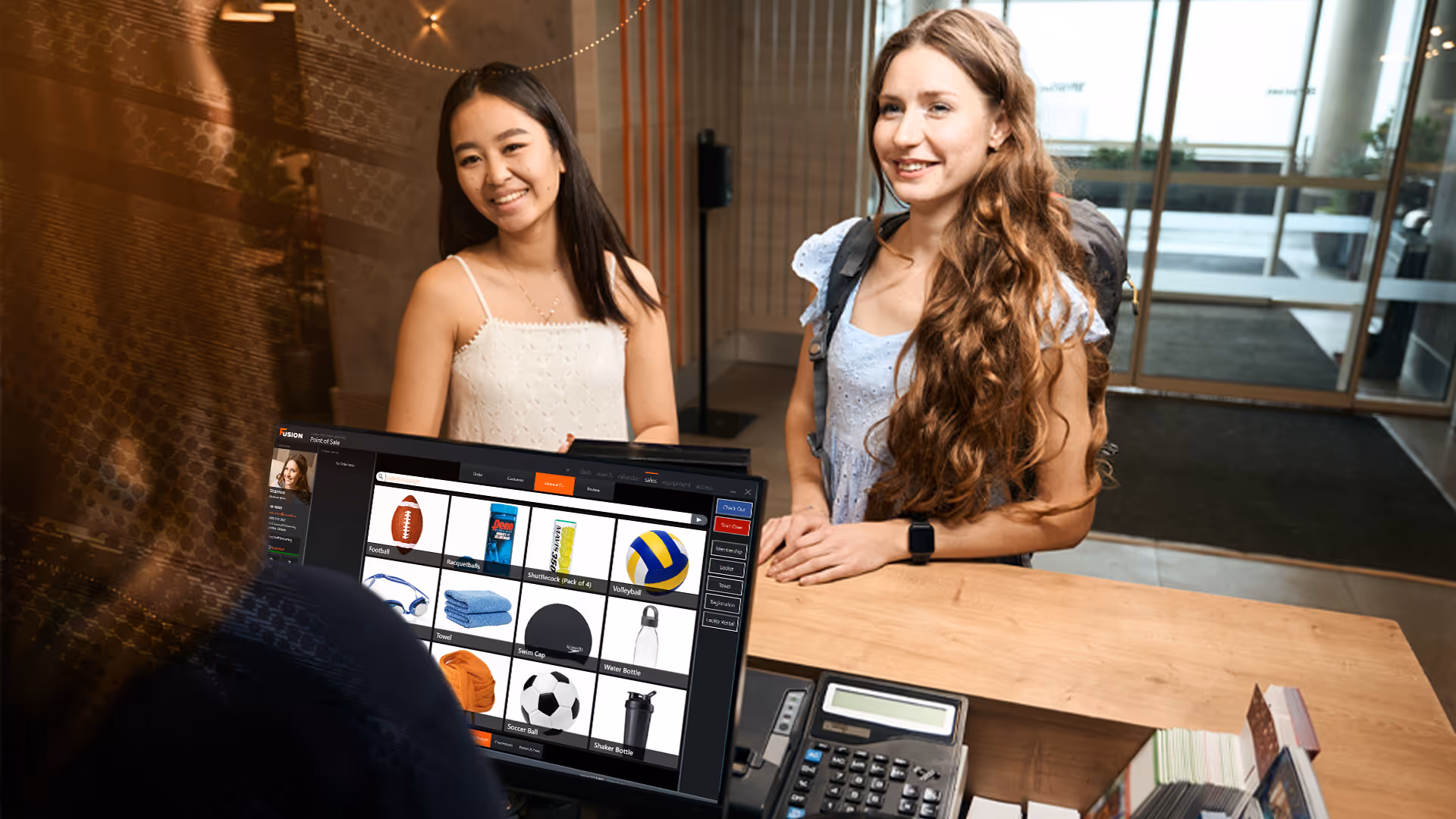 Two female students being assisted by a front desk staff member.