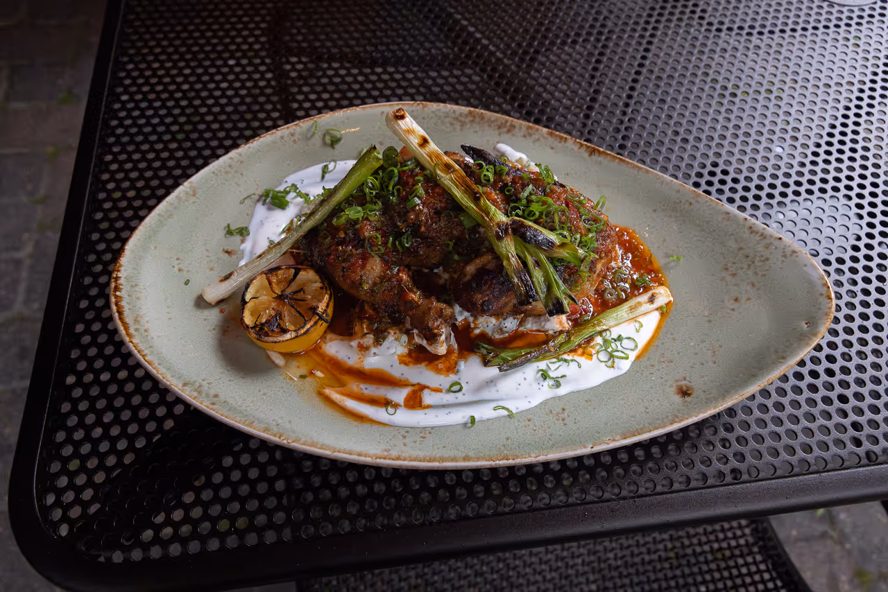 Gourmet ribeye steak with roasted vegetables and charred greens on a rustic plate.