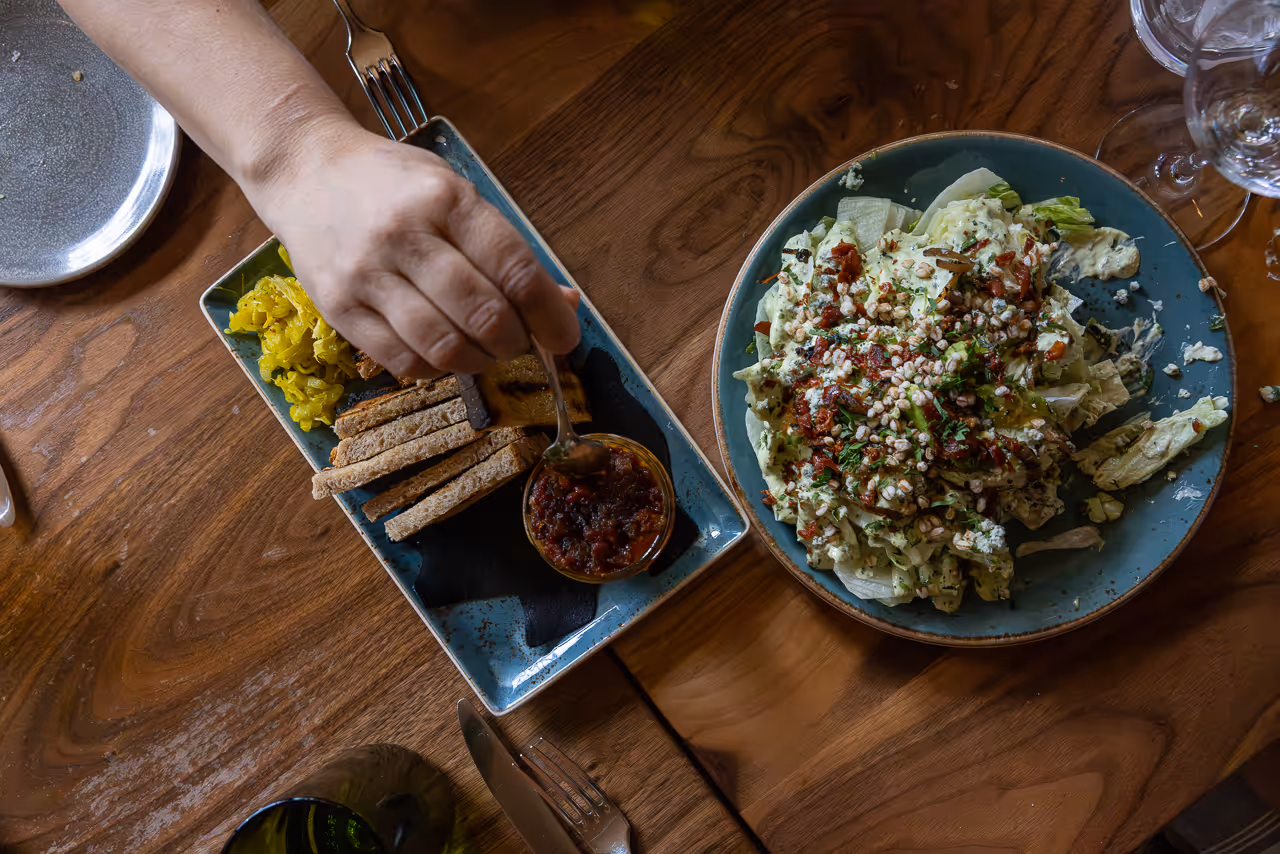 Toasted bread with tapenade and pickles on rustic wooden table.