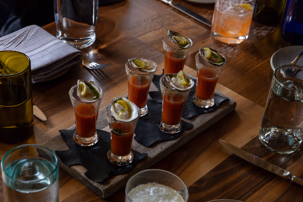 Cocktail with oyster garnish on wooden table.