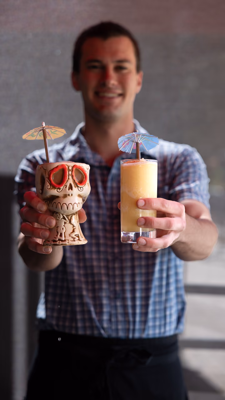 Refreshing tropical cocktail with ice and a pineapple garnish on a wooden table.