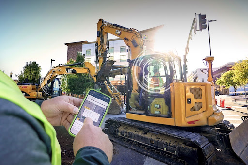Someone managing a large piece of equipment looking at his cell phone demonstrating why SMS has to be part of industrial communication strategies 