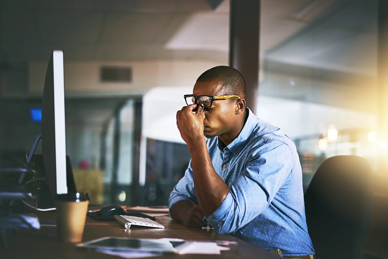 Image of man working at computer, rubbing eyes.