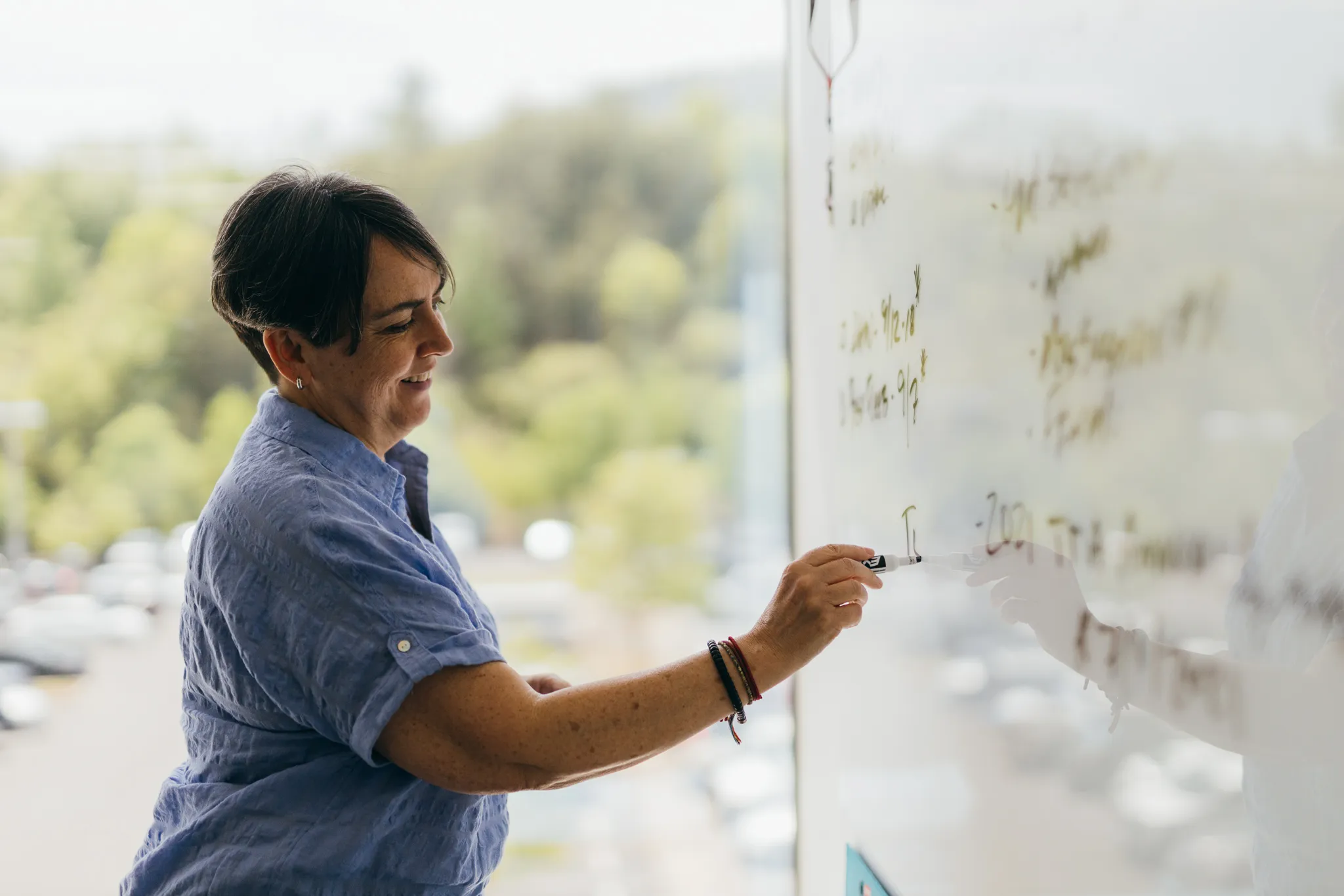 A woman writing on a dry erase board in a meeting room