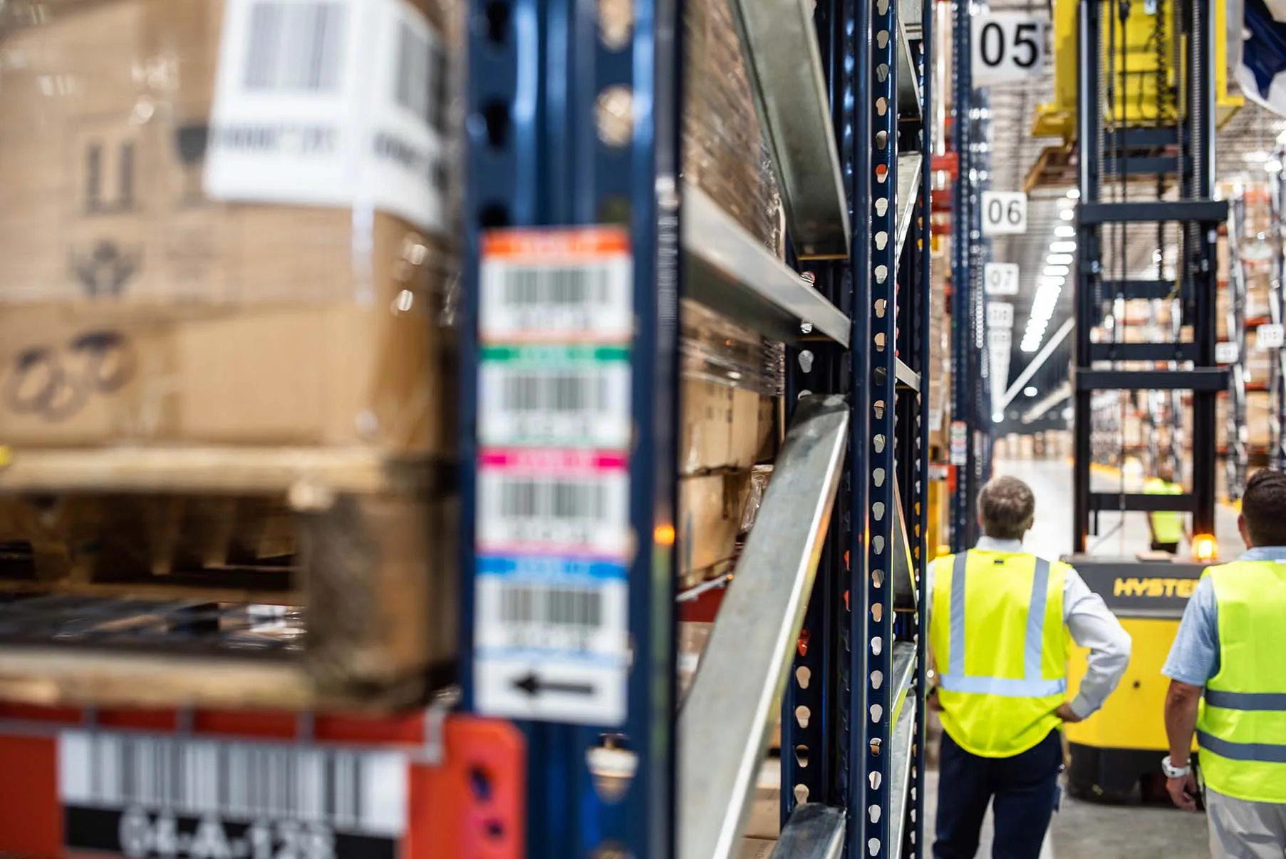 Two working looking at a forklift inside a warehouse