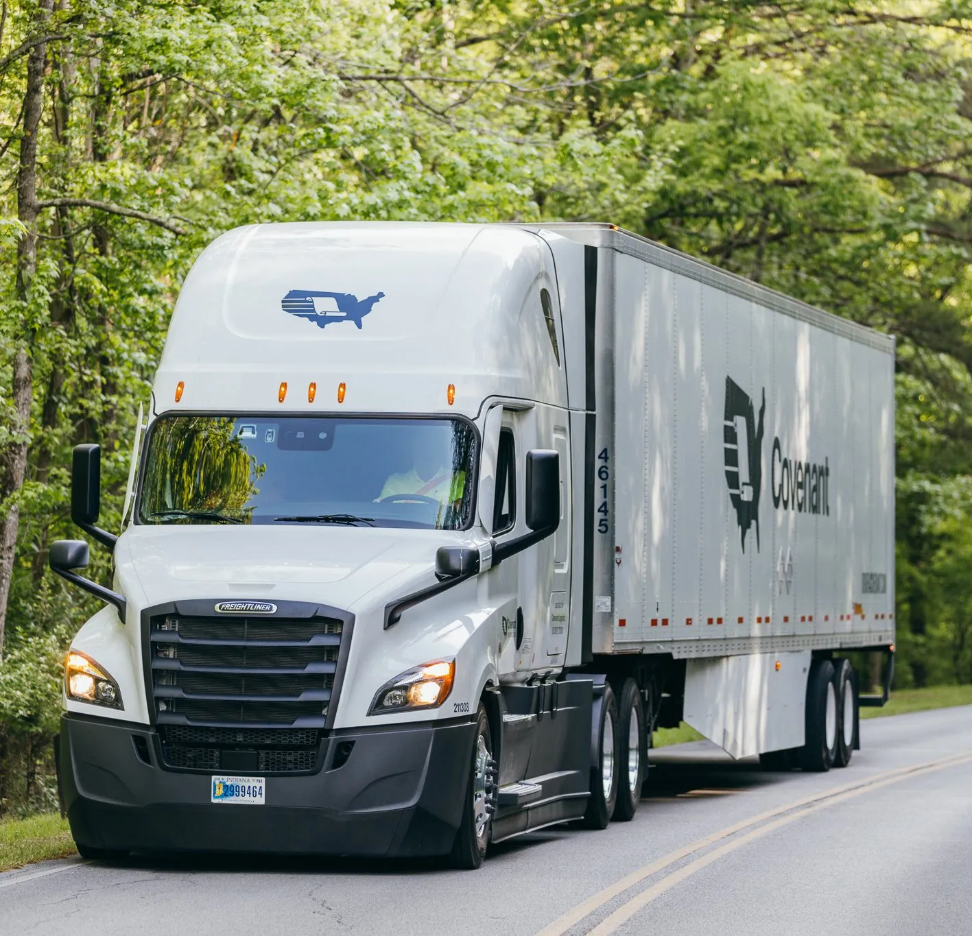 A Covenant Logistics branded semi truck driving on a country road