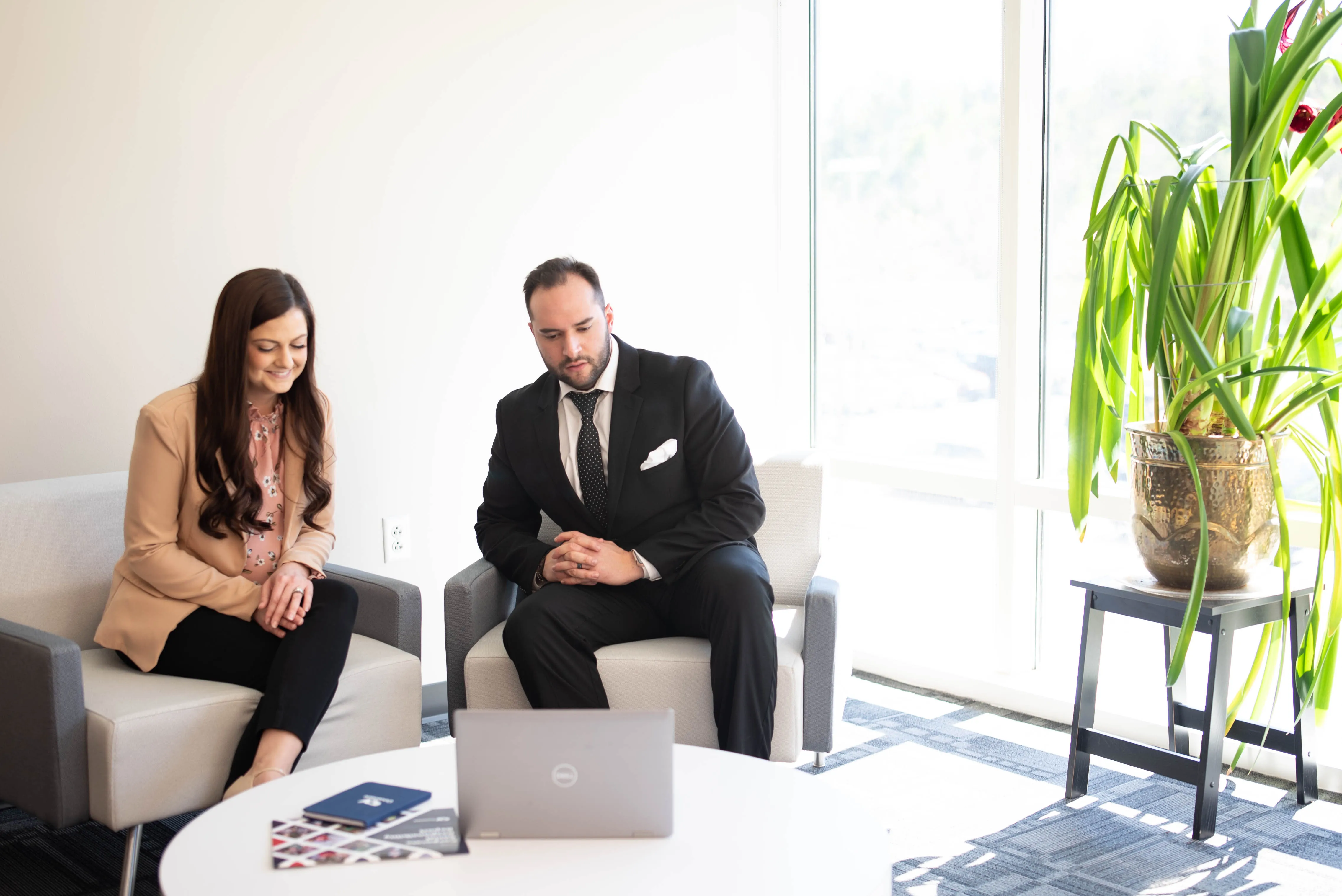 A man and a woman sitting on chairs in an office while on a video call