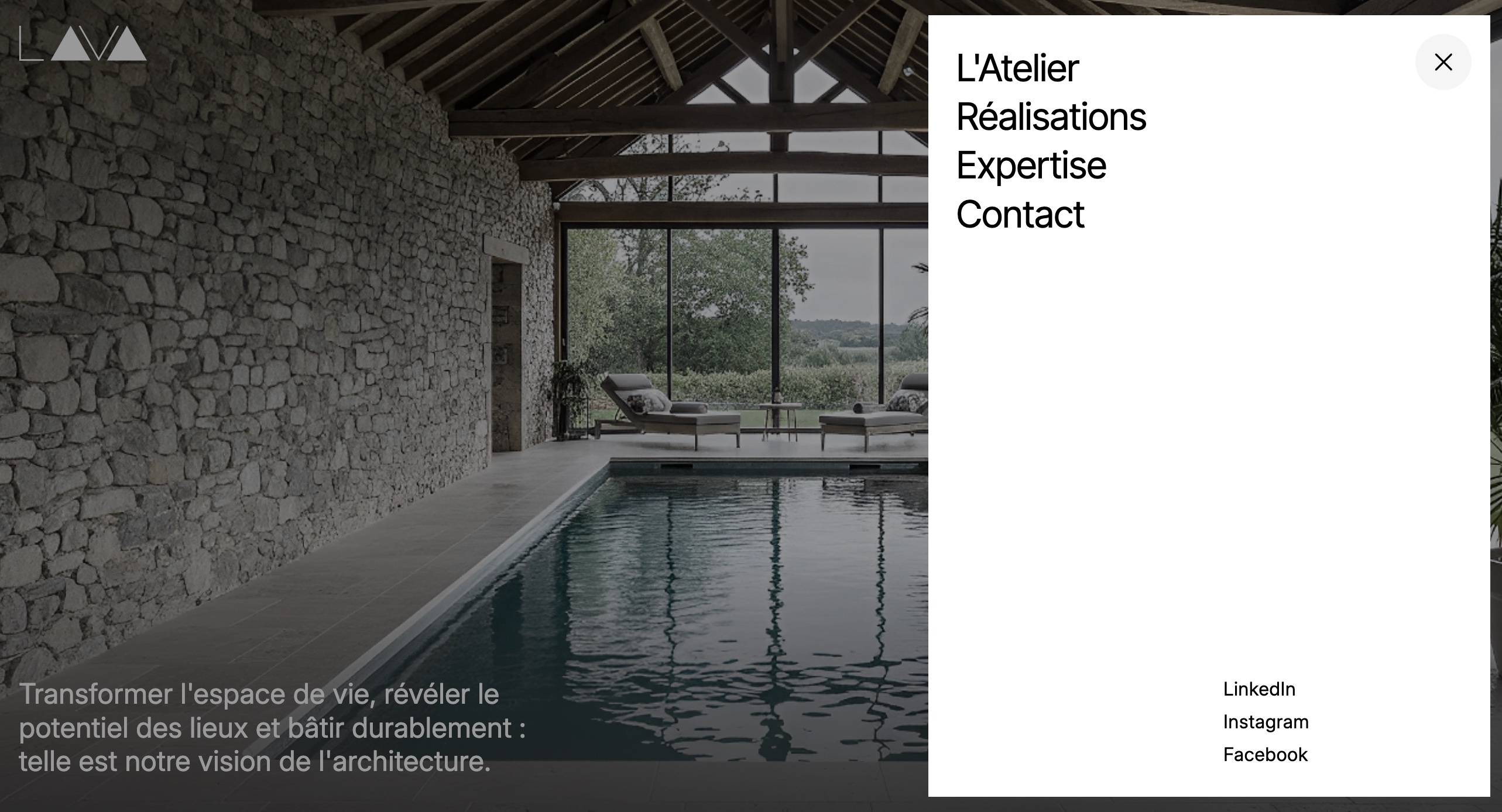 Menu de navigation du site Atelier Lava affiché sur une image d’intérieur architectural avec piscine intérieure, murs en pierre et structure bois.