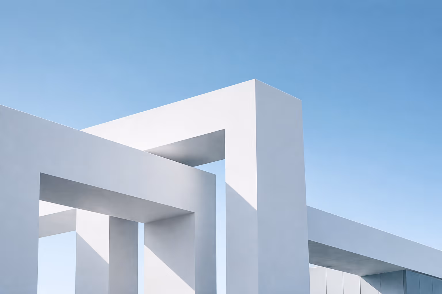 Structure géométrique blanche moderne sous un ciel bleu clair dégagé.