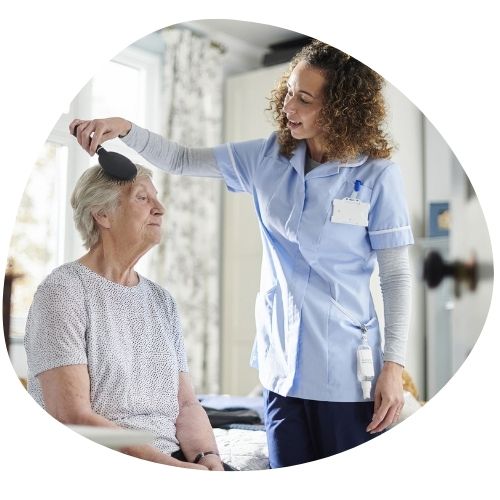 une aide à domicile coiffe une personne âgée
