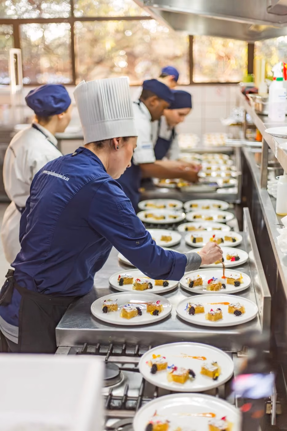 CHS students plating dishes together along the kitchen pass