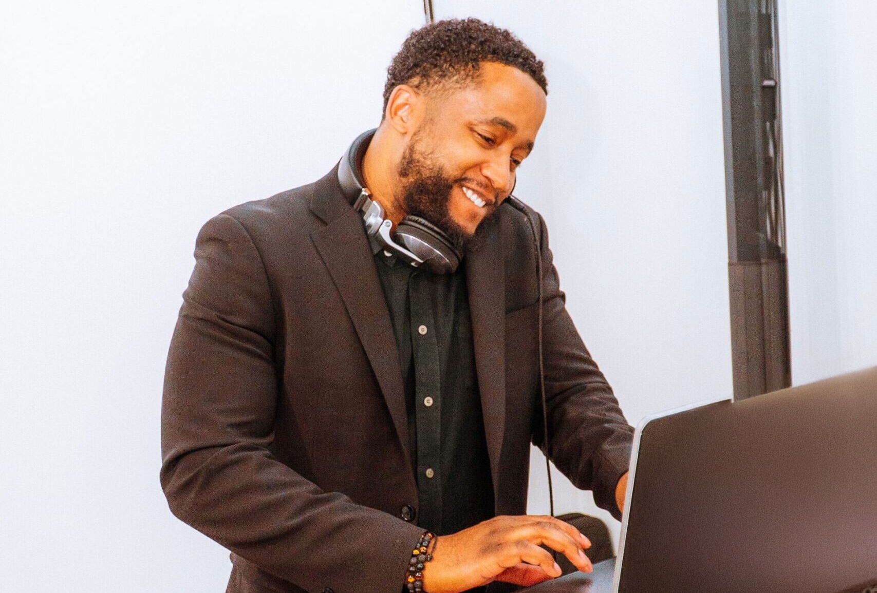 Chicago DJ smiling while preparing music on a laptop, wearing headphones at a private event