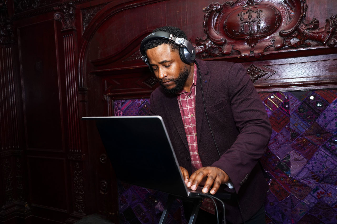 Chicago DJ wearing headphones while mixing music on a laptop in an elegant indoor venue