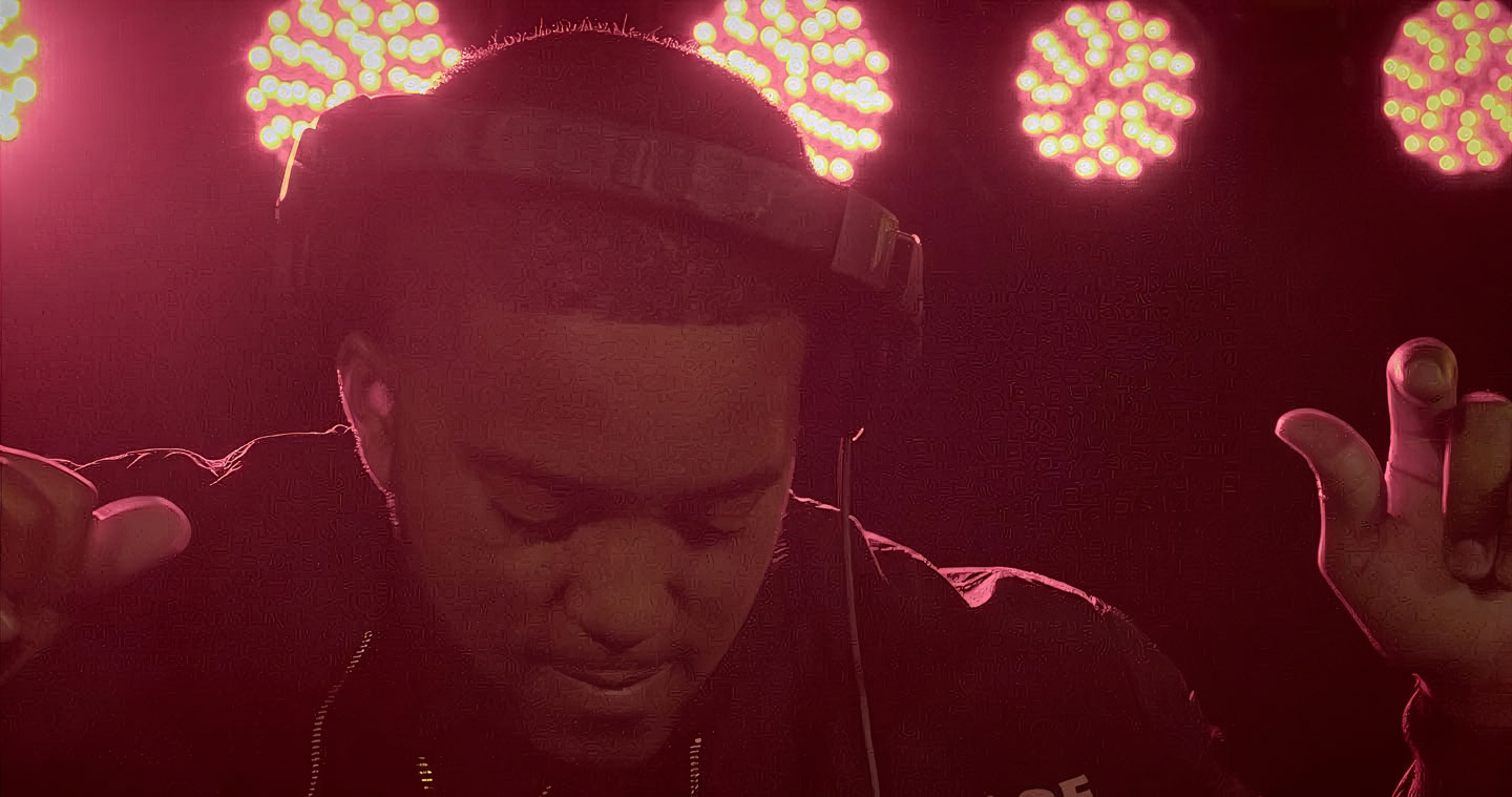 Chicago wedding DJ wearing headphones and mixing live music under stage lighting at a private event