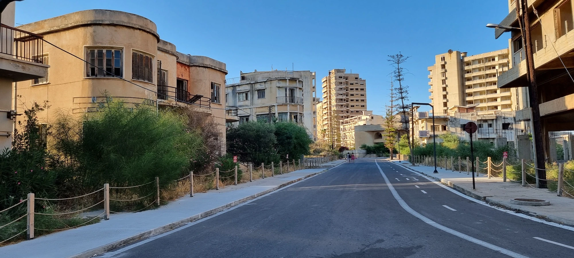 Varosha cyprus, abandoned buildings and whole city is a ghost town after invasion and war, buildings on each side of road derelict with bigger hotels in the distance also derelict