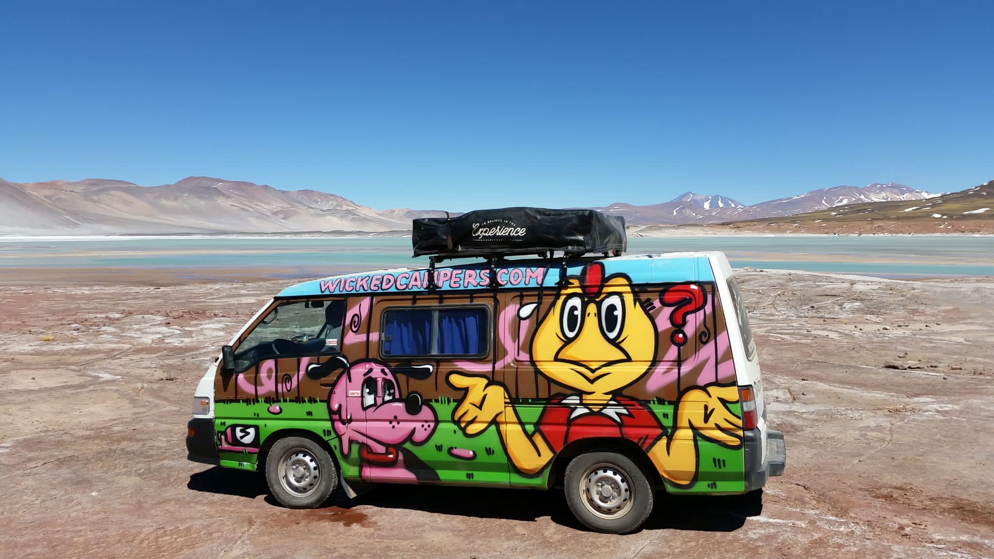 camper van with graffiti in Atacama Desert, Chile has mountains background and flat salt lake