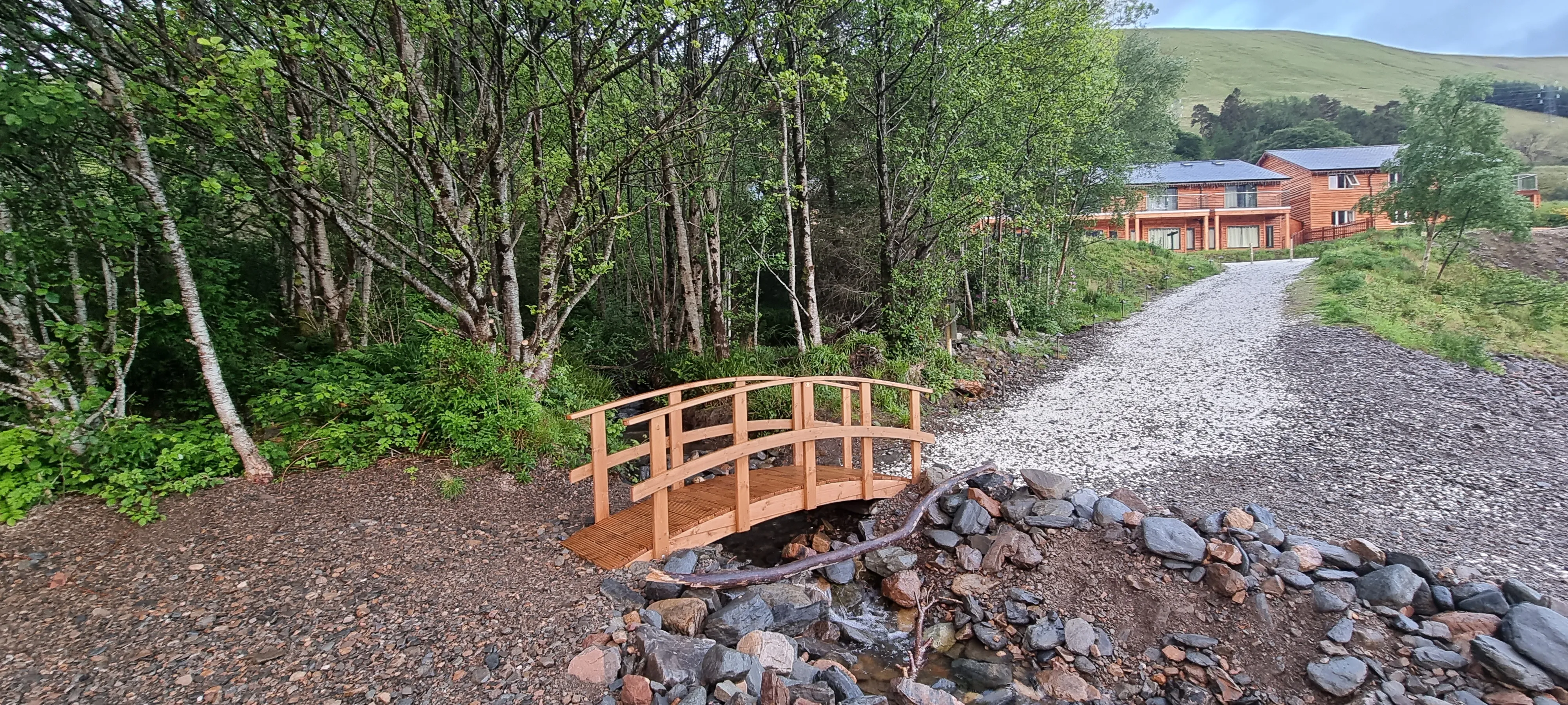 a small bridge and a lake and mountains in the distance