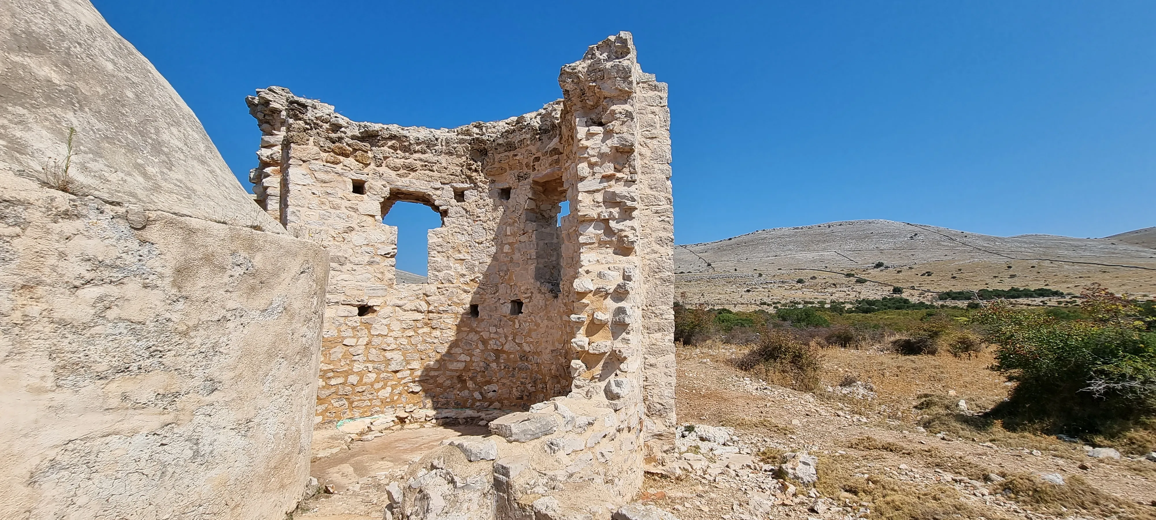 an old abandoned church on one of the islands of kornati national park croatia, blue skies hilly background, rugged and desert like terrain with broken down church, the gymsy traveller