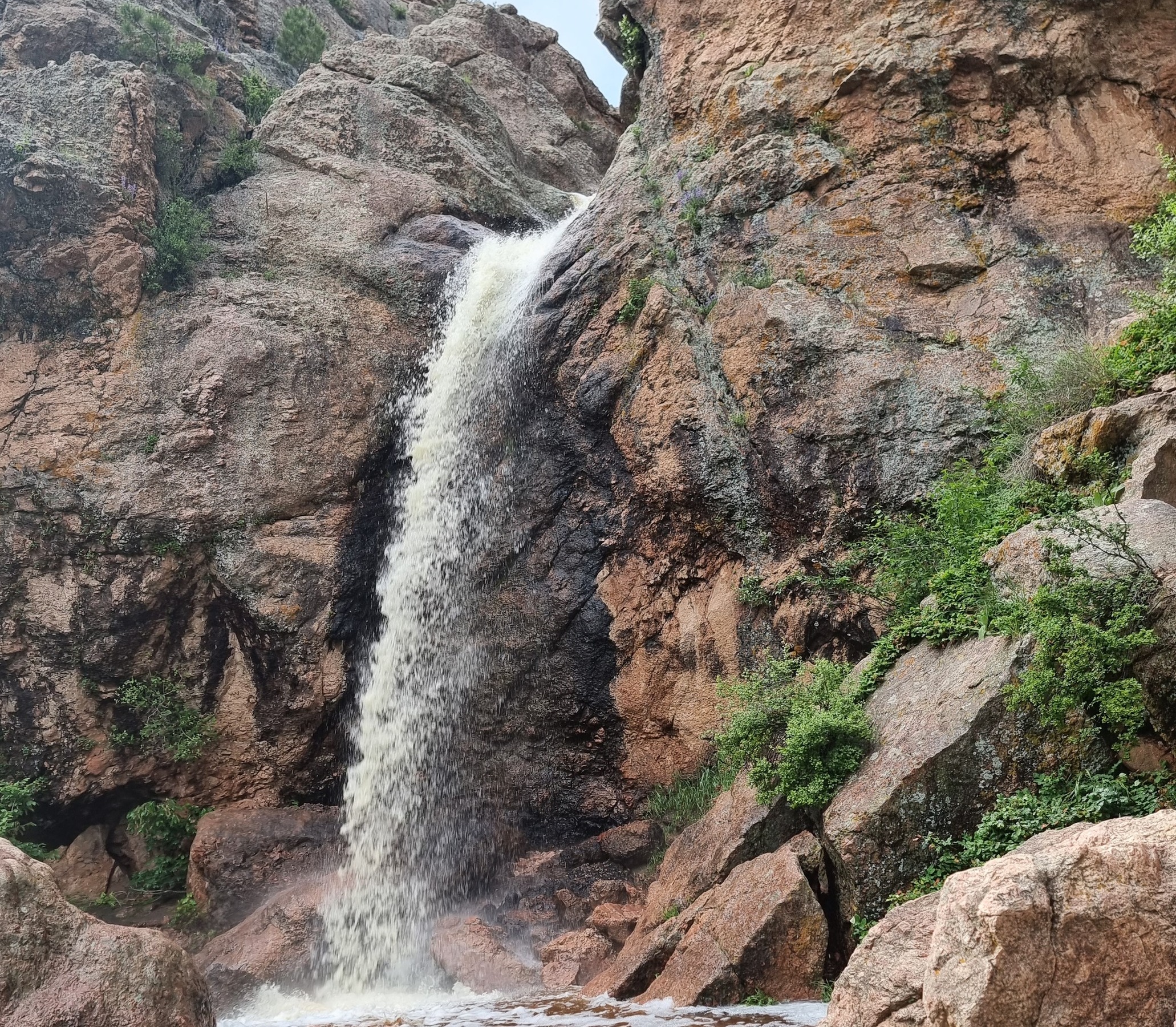 a waterfall at the end of the horsetooth falls trail, water falling at the edge of a rocky surface into a murky but serene pool. Image was take from low y the pool looking u sideways at the waterfall. thegymsytraveller in waterfall, colorado