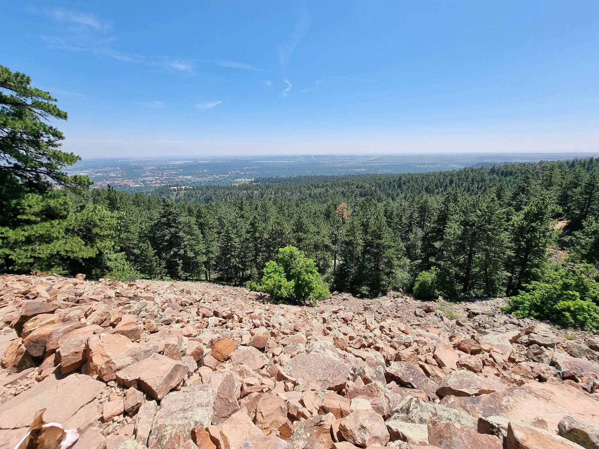 boulder flatirons, colorado. rocks make up the path in view, image taken from high up and a vast view can be seen of boulder and beyond. clear skies.