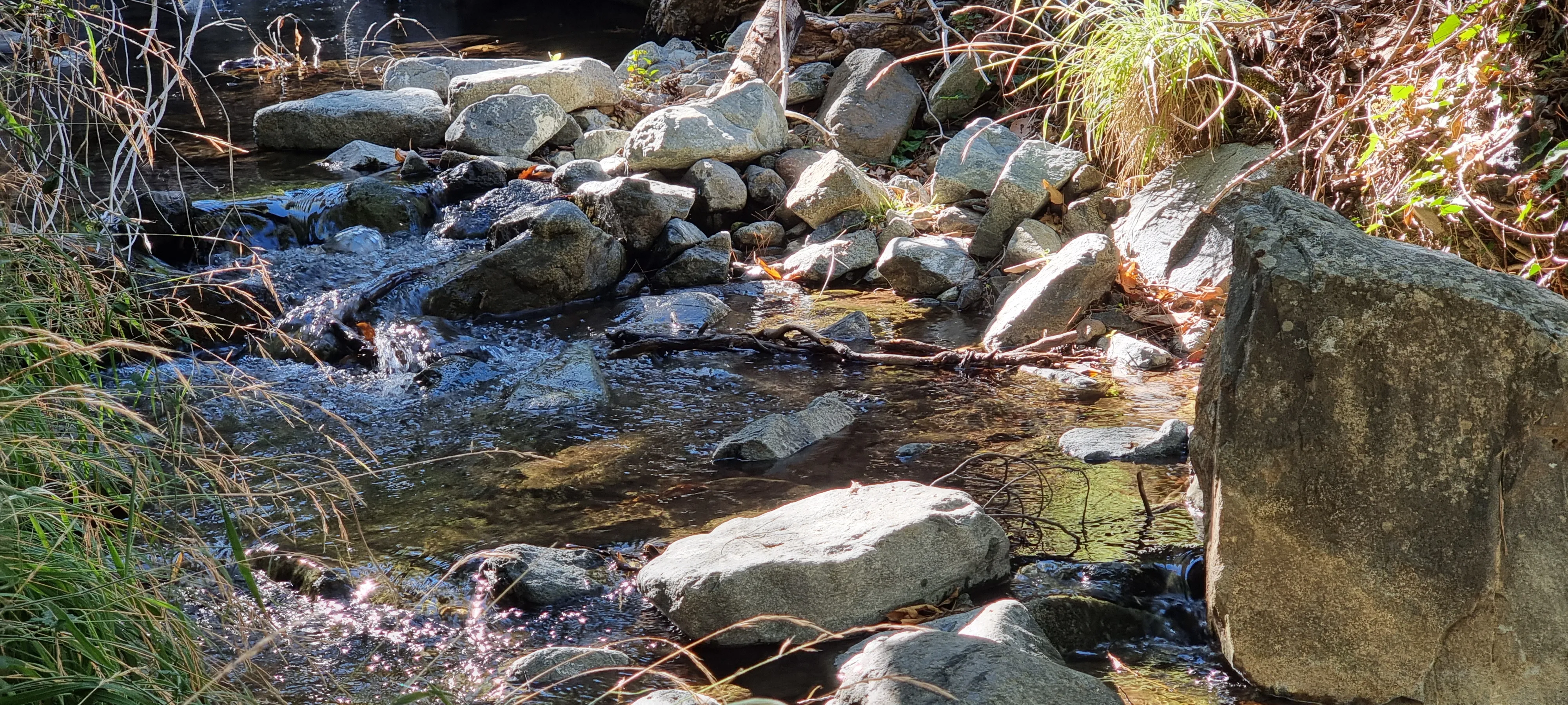 a small pond with rocks and boulders surrounding it. kaledonia falls path to the waterfall in troodos mountains in cyprus.c 