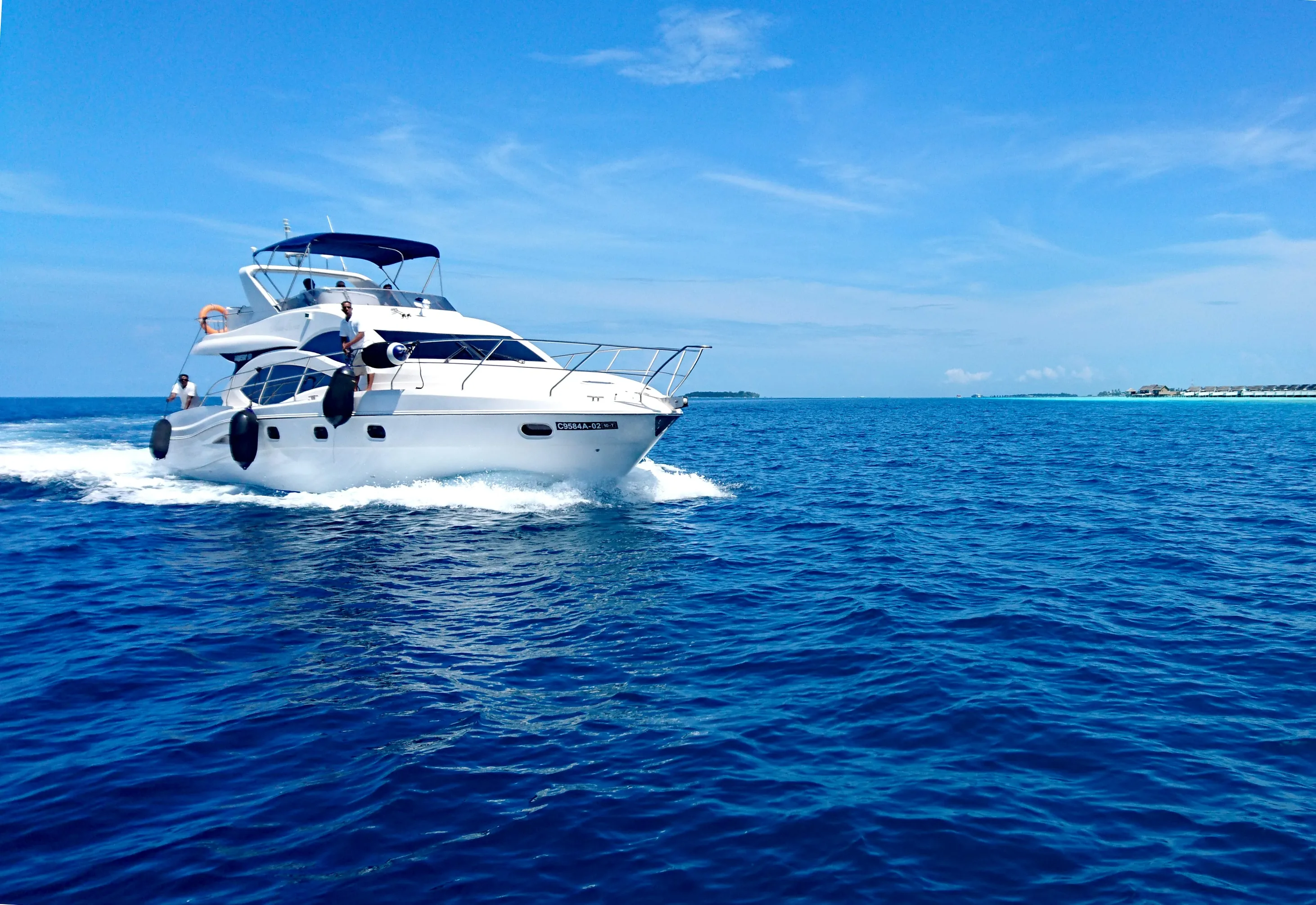 a yacht in the middle of an ocean with a bay in the distance, clear summer skies