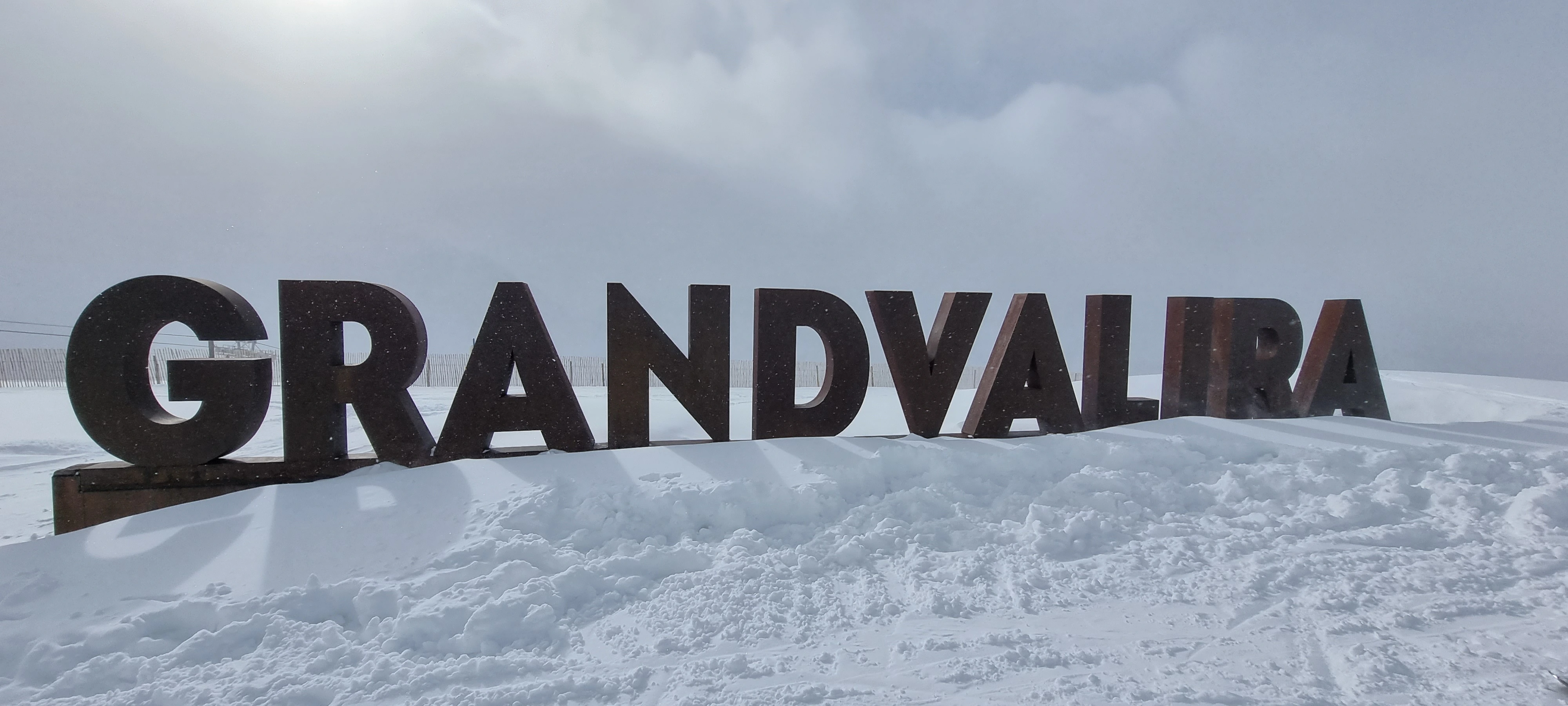 a giant sign that says Grandvalira on the mountain of the Andorran mountain and ski resort. Snow covers the surroundings.
