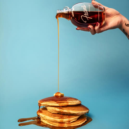 Stack of pancakes with syrup being poured on