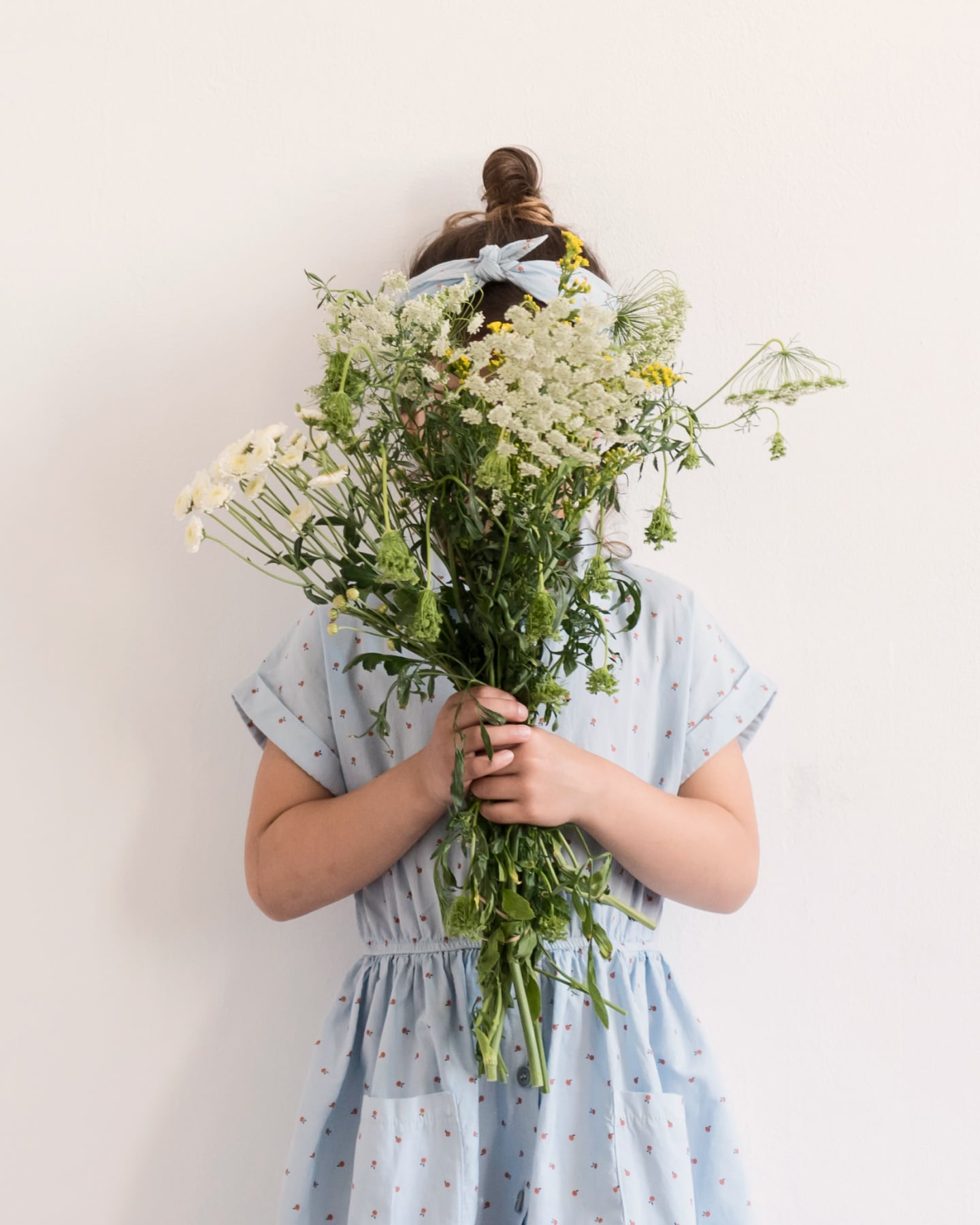 A girl wearing a blue dress holding flowers.