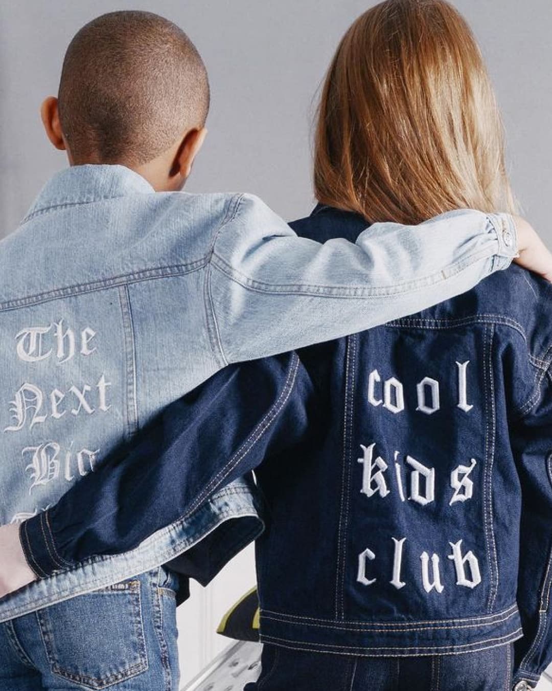 A boy and a girl wearing matching denim jackets.