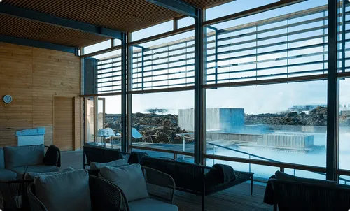 Spacious room with large windows overlooking a steaming outdoor pool and rocky landscape.