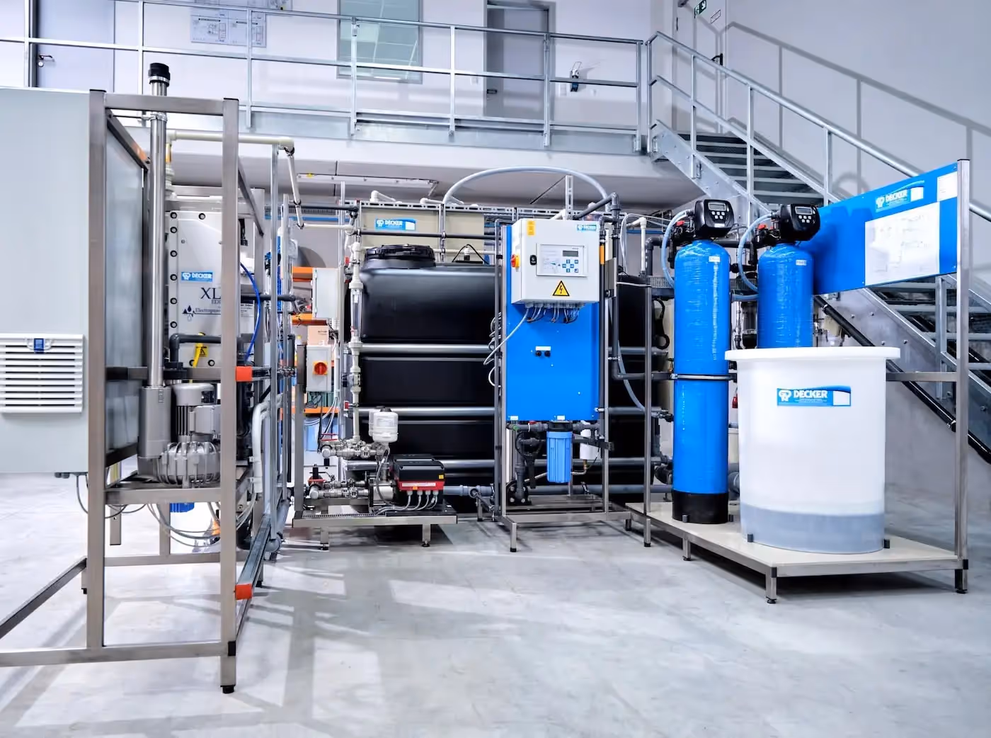 A large water treatment system with various tanks and control panels is installed in an industrial setting.