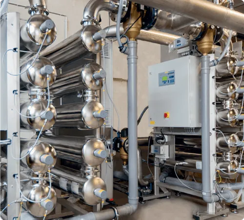 Industrial machine with multiple large metal pipes and a control panel on the side.