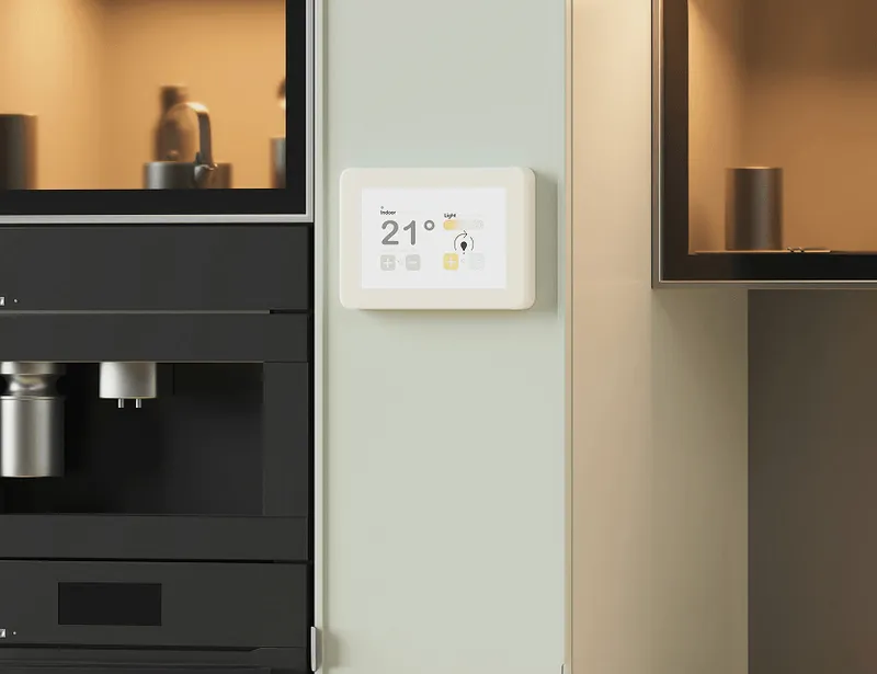 A digital thermostat on a wall displays a temperature of 21 degrees Celsius.