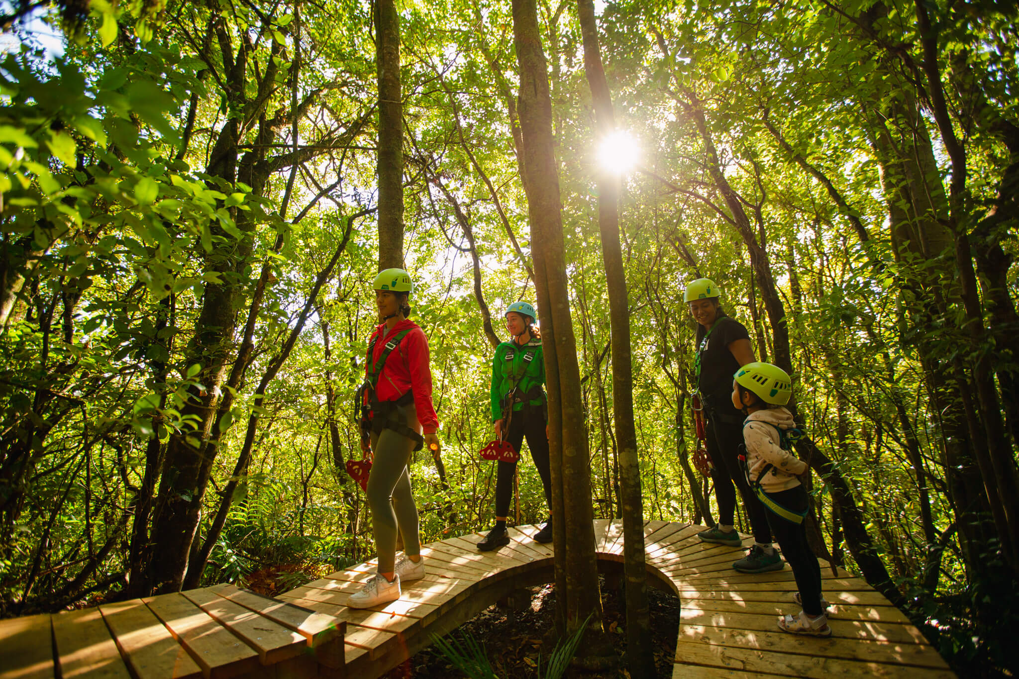 people lining up in the forest for their turn at the zipline