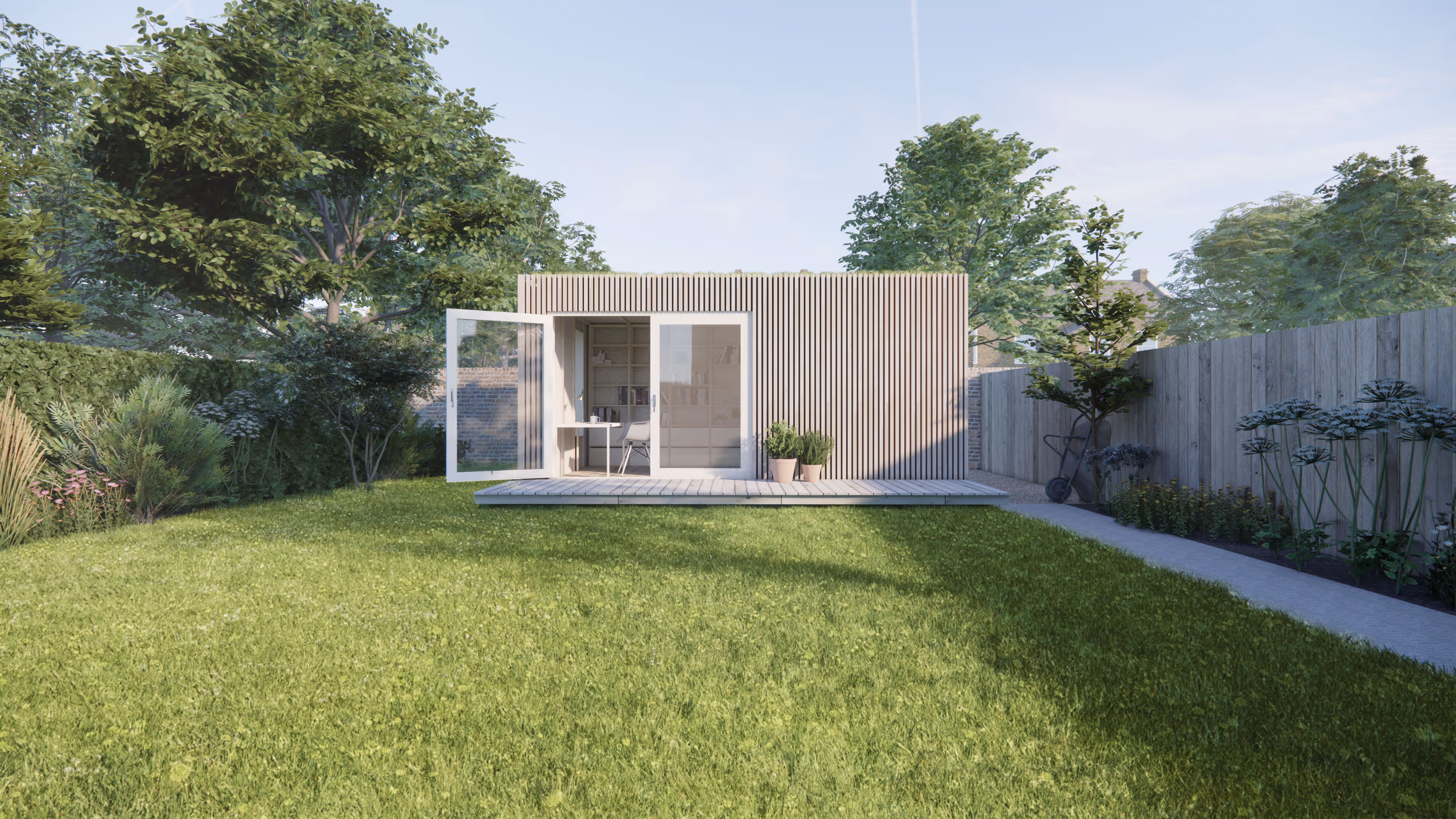 A timber clad studio space sits at the end of a garden. A wide glass door is open onto a deck at its front, and inside a chair next to a desk.