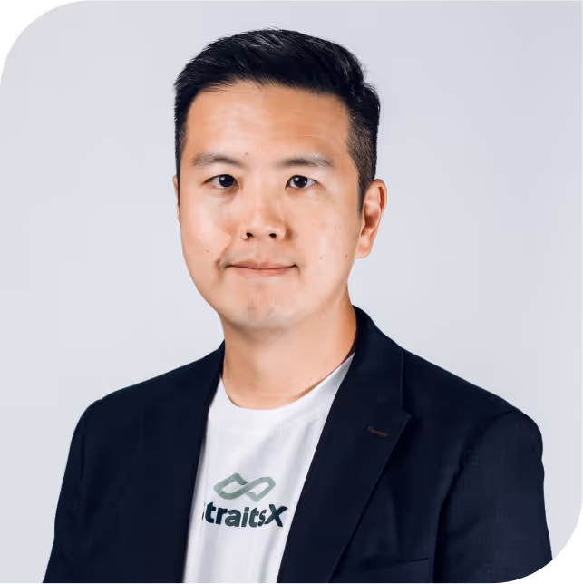 Portrait of Daniel Lee, team member at StraitsX, dressed in a navy blazer against a neutral background.