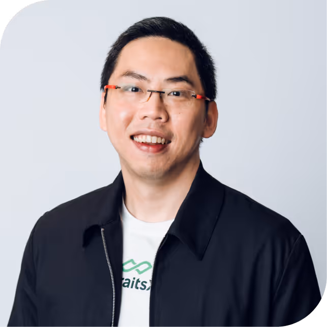 Portrait of Mark Hew, team member at StraitsX, dressed in a navy blazer against a neutral background.
