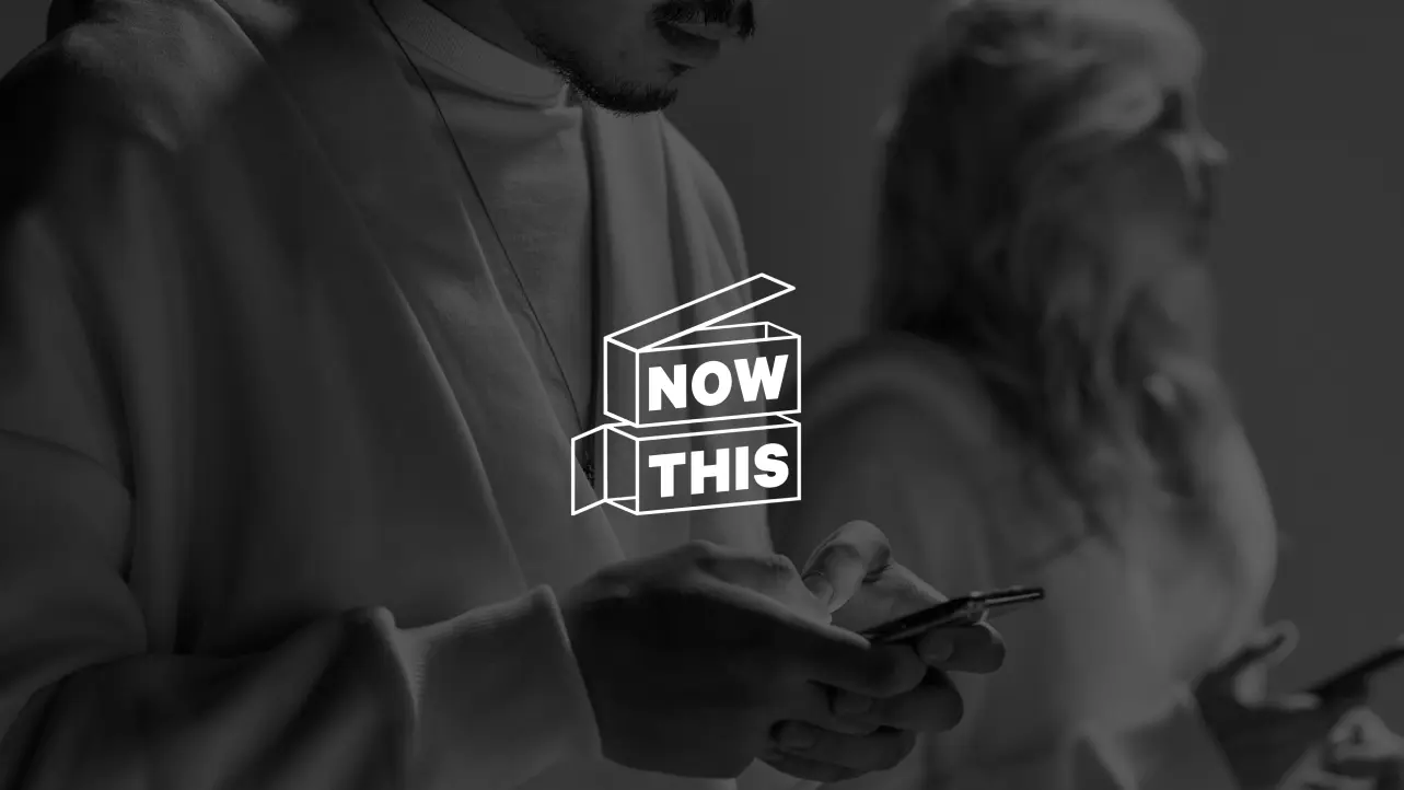 Two people looking at smartphones with a white Now This logo overlay in the center.